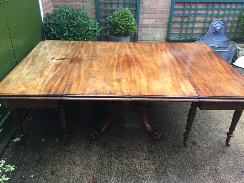 An early nineteenth-century George IV Irish mahogany extending dining table featuring a central pedestal base and turned support legs with brass castors. View XV