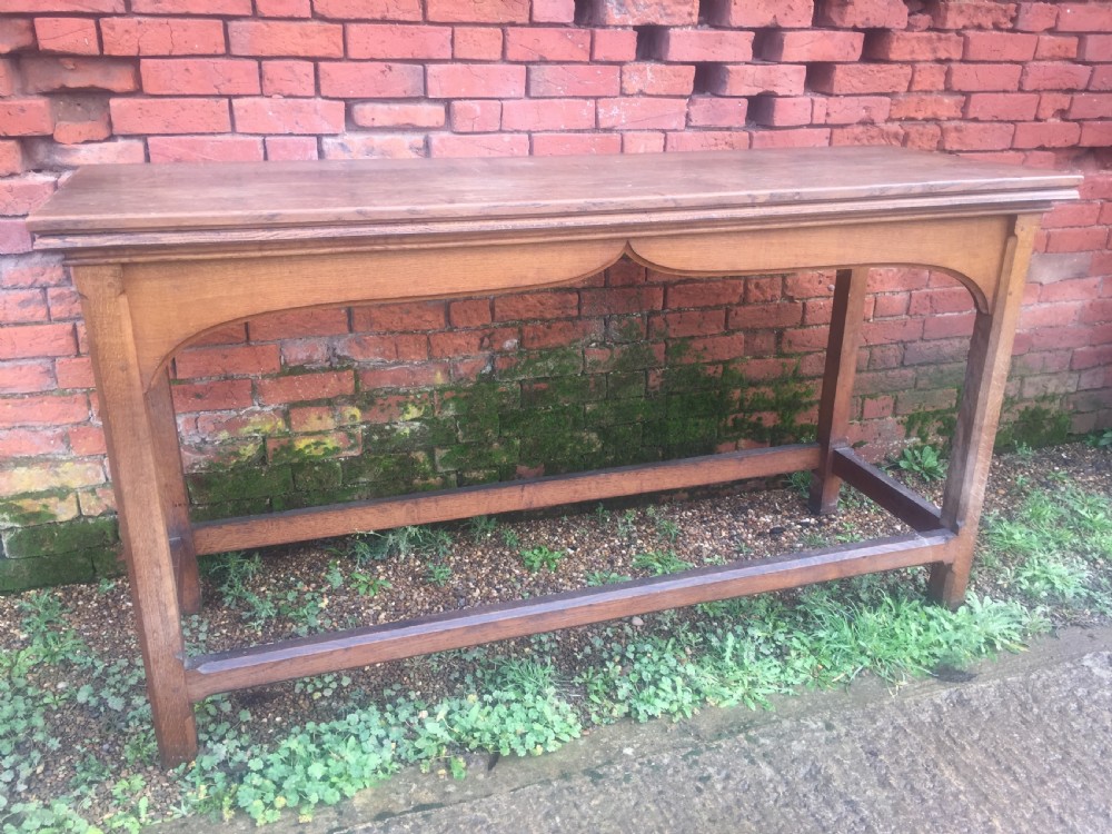 A rectangular oak serving table featuring a moulded top, shaped arched apron, square legs, and perimeter stretchers. View II