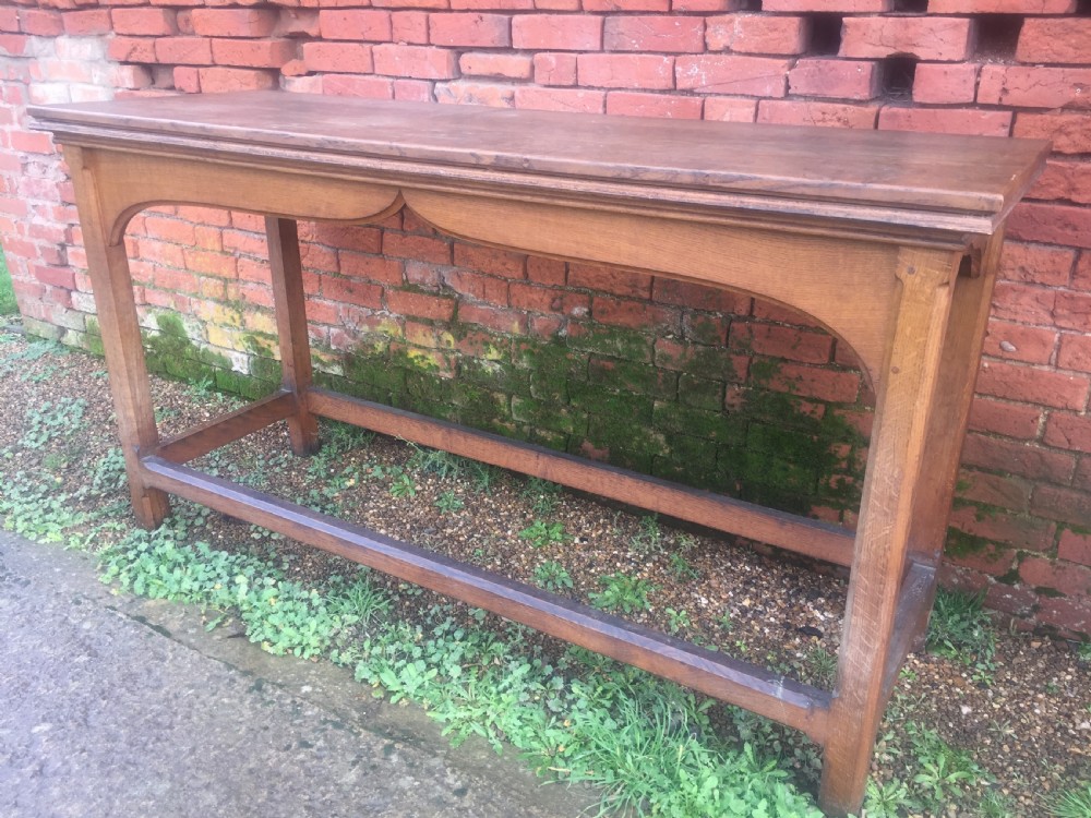 A rectangular oak serving table featuring a moulded top, shaped arched apron, square legs, and perimeter stretchers. View III