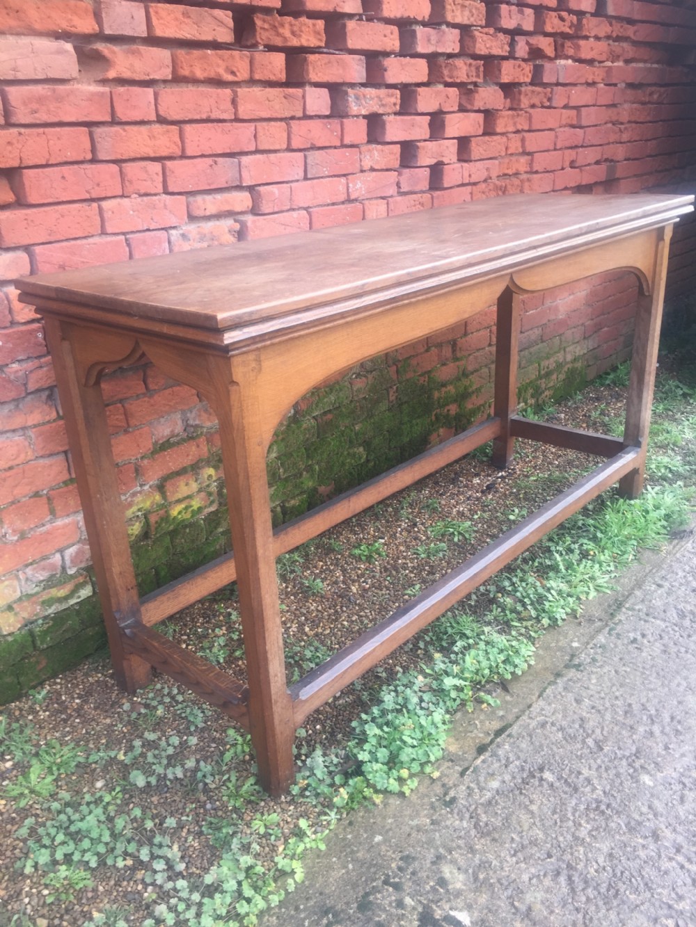 A rectangular oak serving table featuring a moulded top, shaped arched apron, square legs, and perimeter stretchers. View XI