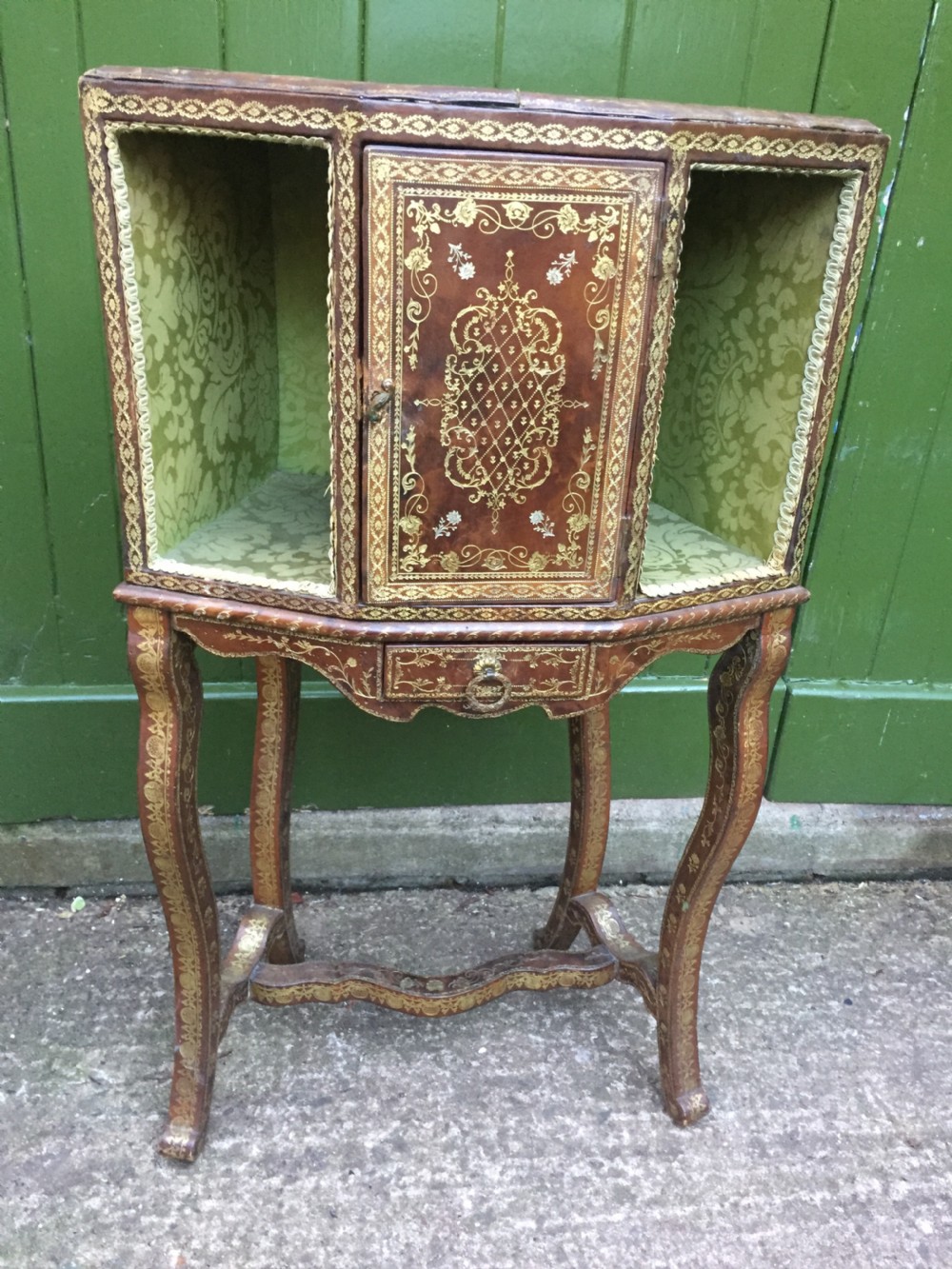 An early twentieth-century French accent table encased in chestnut brown leather with gold leaf tooling, featuring a central cupboard door, open side compartments lined in green damask silk, a small drawer, and cabriole legs. View II