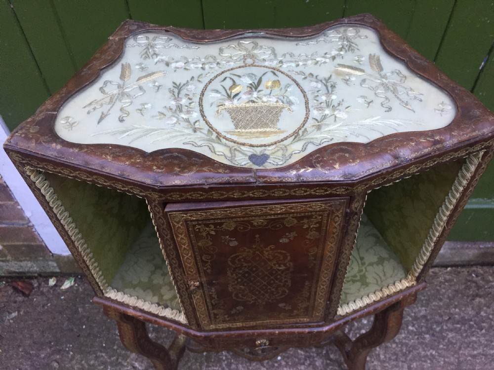 An early twentieth-century French accent table encased in chestnut brown leather with gold leaf tooling, featuring a central cupboard door, open side compartments lined in green damask silk, a small drawer, and cabriole legs. View V