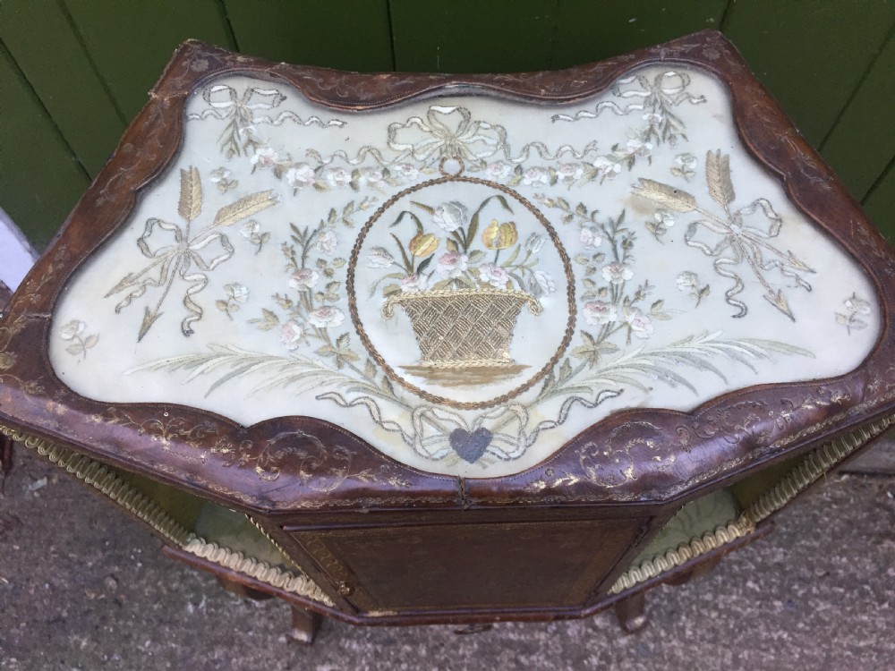An early twentieth-century French accent table encased in chestnut brown leather with gold leaf tooling, featuring a central cupboard door, open side compartments lined in green damask silk, a small drawer, and cabriole legs. View XII