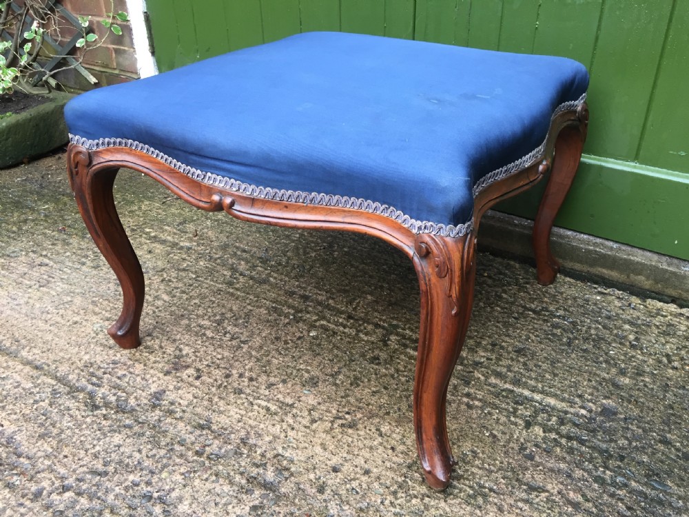 A large mid-nineteenth-century square Victorian stool featuring carved walnut cabriole legs and a blue upholstered top trimmed with gimp braid. View X