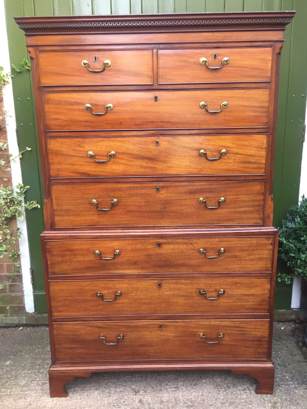 A late eighteenth-century George III mahogany chest-on-chest featuring a dentil moulding cornice, two short over five long graduated drawers with brass swan-neck handles, supported on bracket feet. View II