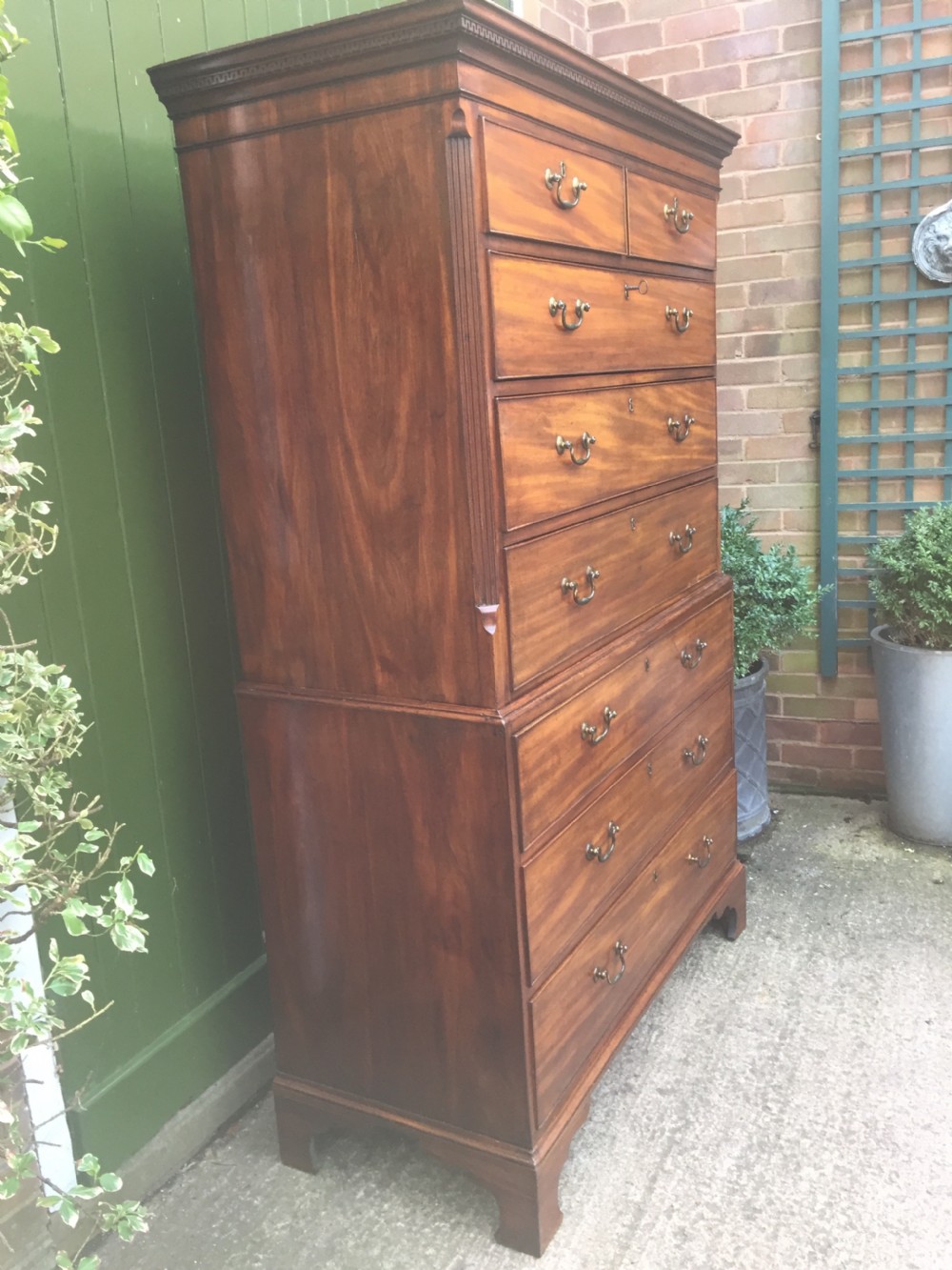 A late eighteenth-century George III mahogany chest-on-chest featuring a dentil moulding cornice, two short over five long graduated drawers with brass swan-neck handles, supported on bracket feet. View V