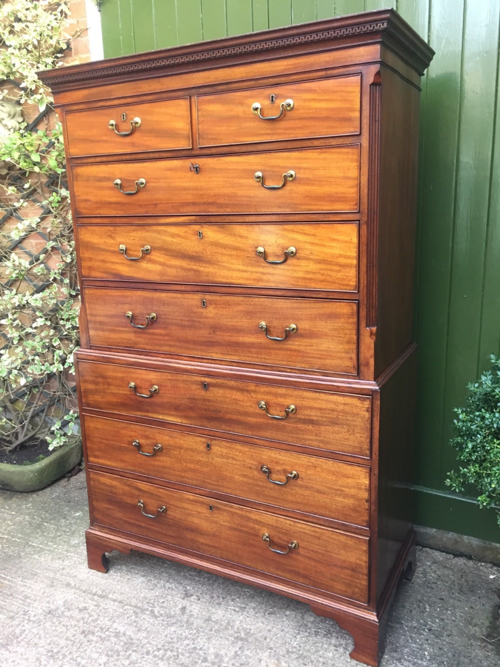 A late eighteenth-century George III mahogany chest-on-chest featuring a dentil moulding cornice, two short over five long graduated drawers with brass swan-neck handles, supported on bracket feet. View IX