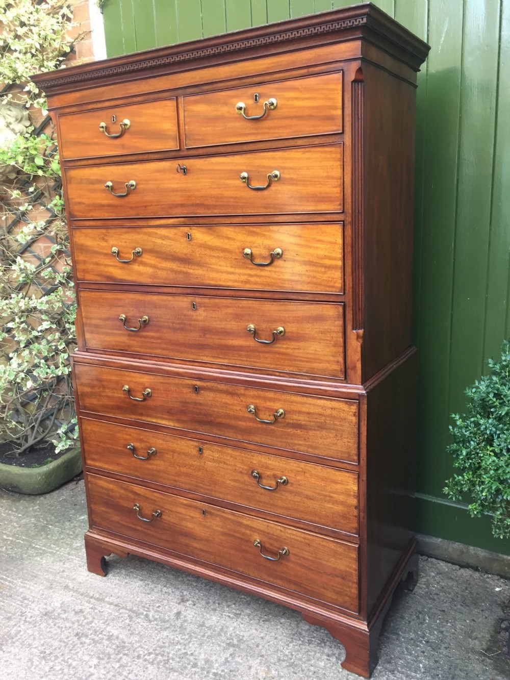 A late eighteenth-century George III mahogany chest-on-chest featuring a dentil moulding cornice, two short over five long graduated drawers with brass swan-neck handles, supported on bracket feet. View XII