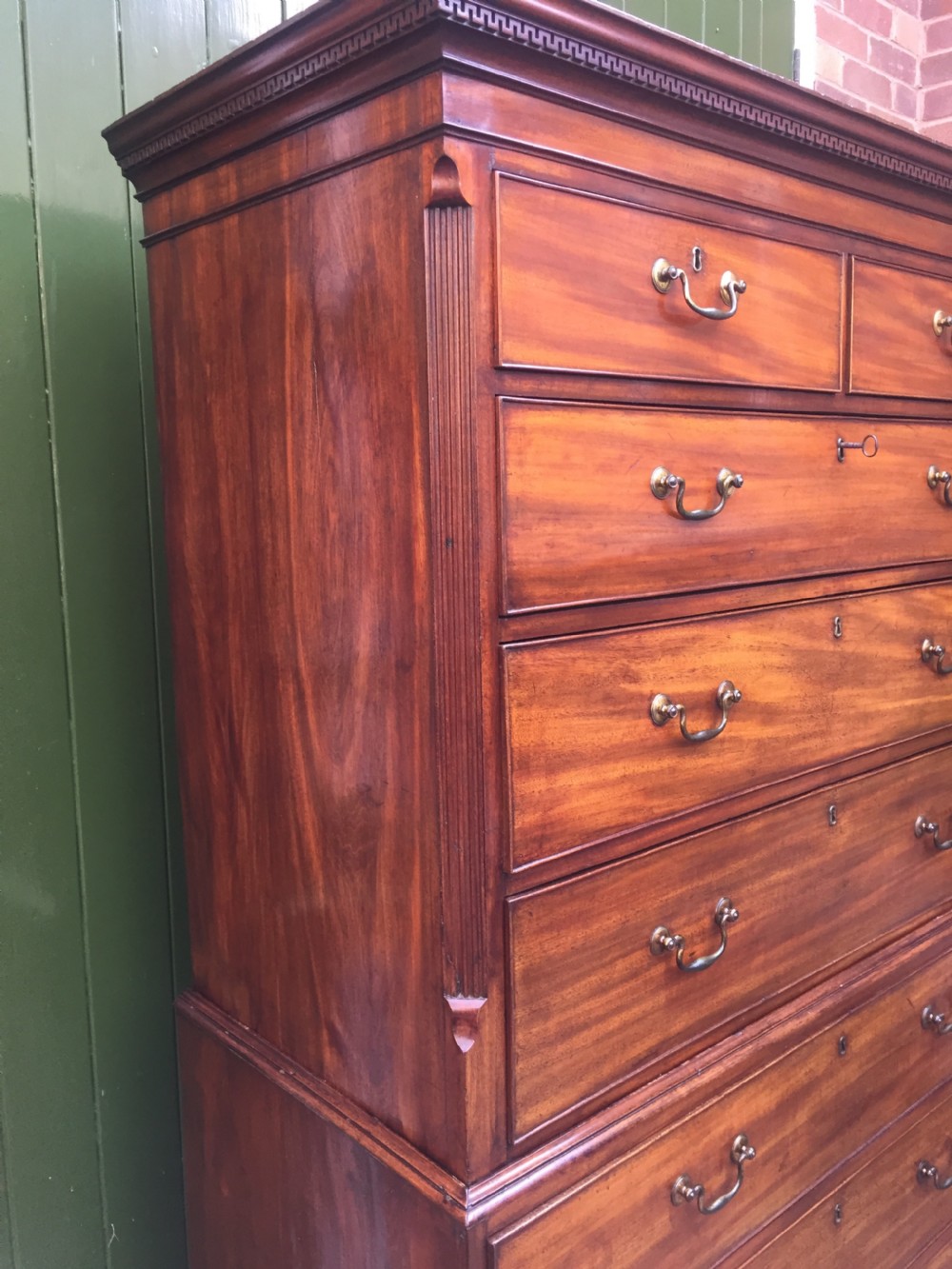 A late eighteenth-century George III mahogany chest-on-chest featuring a dentil moulding cornice, two short over five long graduated drawers with brass swan-neck handles, supported on bracket feet. View XVII