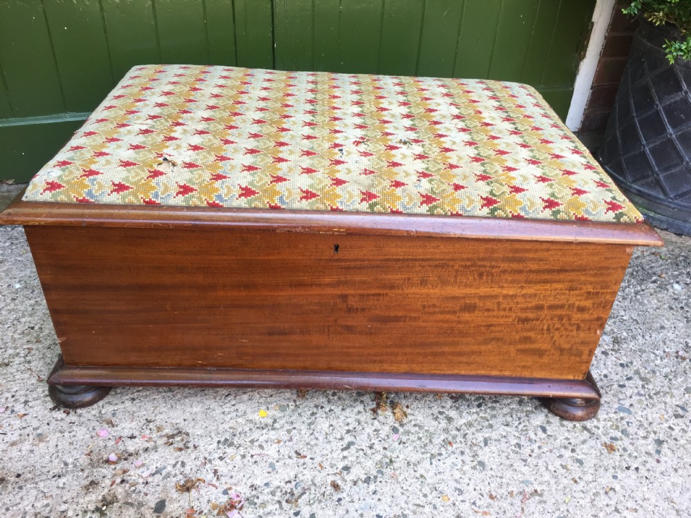 A mid-19th-century mahogany storage ottoman featuring a geometric gros-point needlework upholstered top resting on low turned bun feet. View II