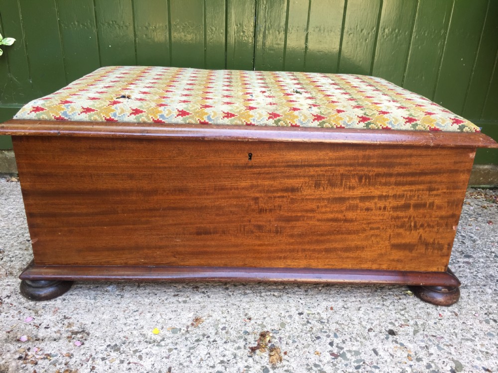 A mid-19th-century mahogany storage ottoman featuring a geometric gros-point needlework upholstered top resting on low turned bun feet. View VI