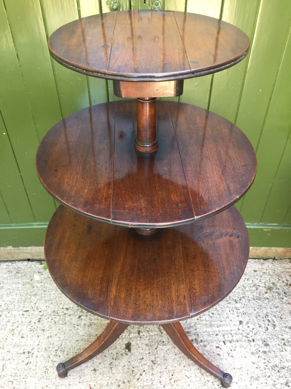 A late 18th-century George III mahogany three-tier circular dumb waiter featuring folding drop-leaf surfaces and a tripod base on castors. View VI