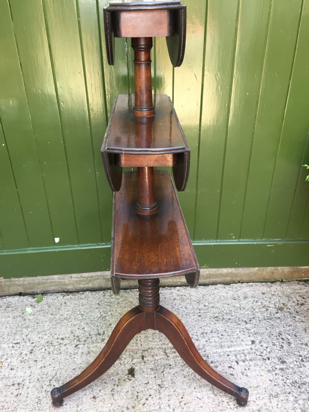 A late 18th-century George III mahogany three-tier circular dumb waiter featuring folding drop-leaf surfaces and a tripod base on castors. View VIII