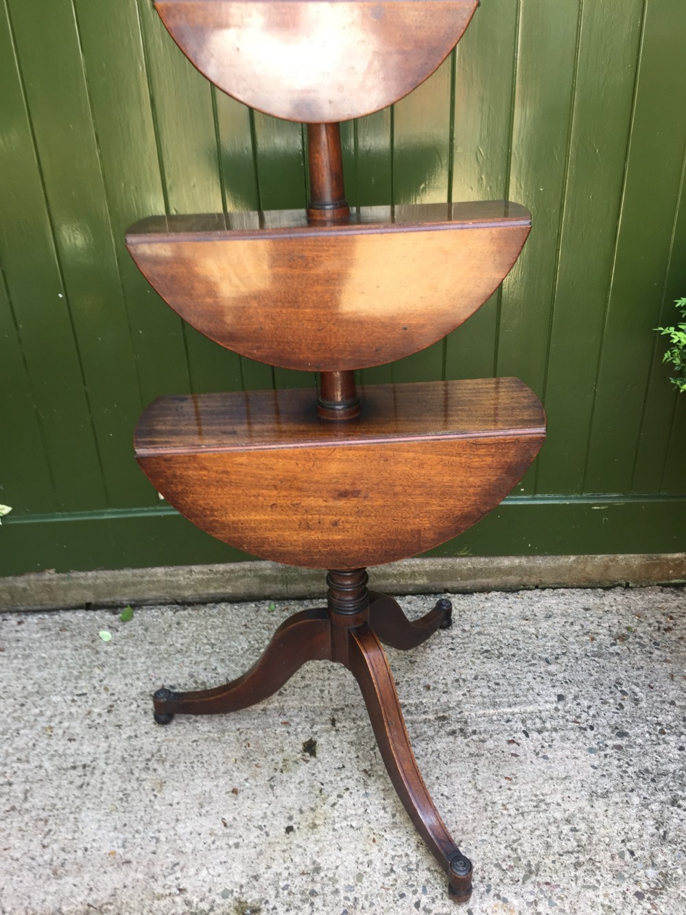 A late 18th-century George III mahogany three-tier circular dumb waiter featuring folding drop-leaf surfaces and a tripod base on castors. View IX