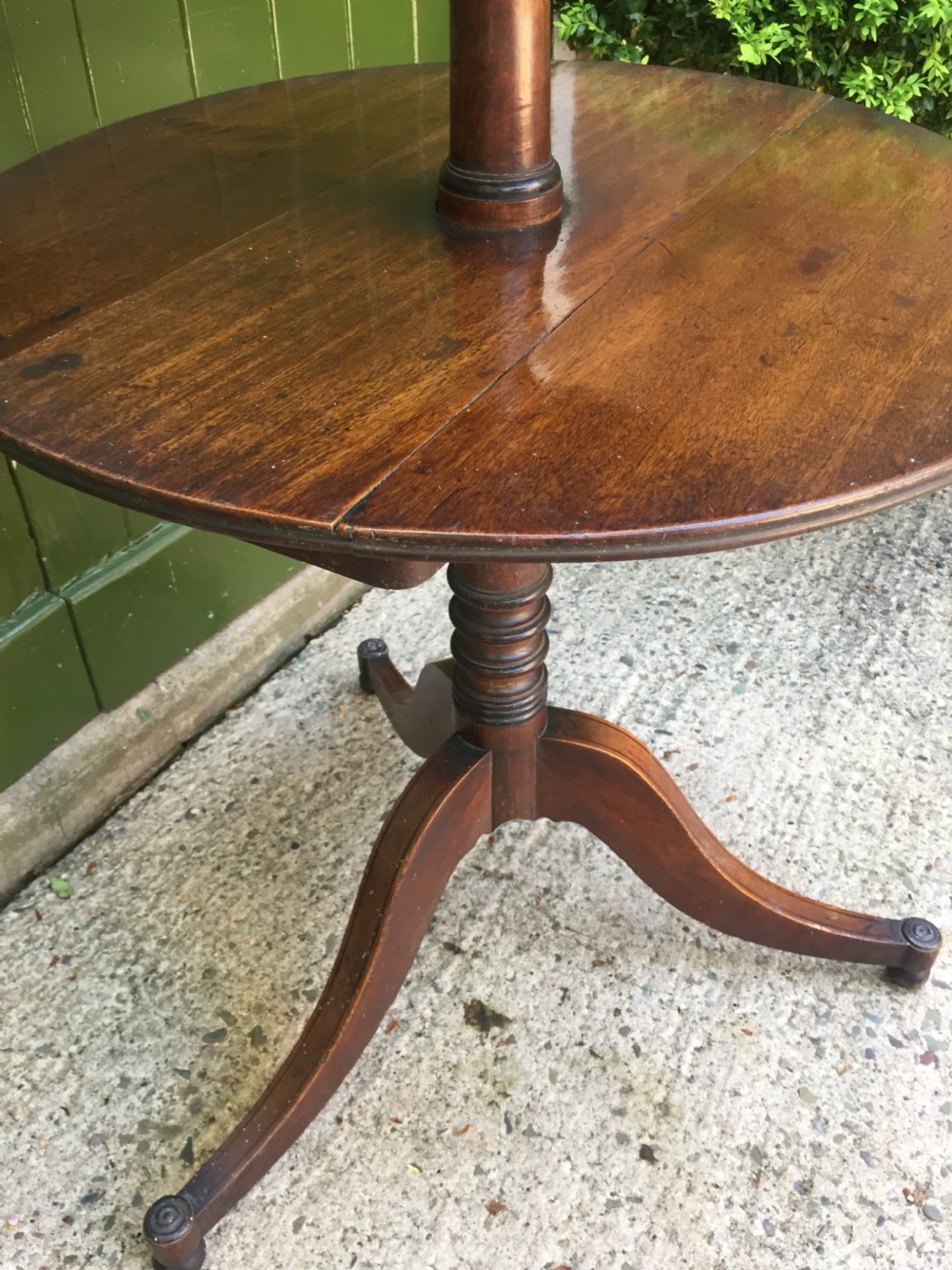 A late 18th-century George III mahogany three-tier circular dumb waiter featuring folding drop-leaf surfaces and a tripod base on castors. View XIII