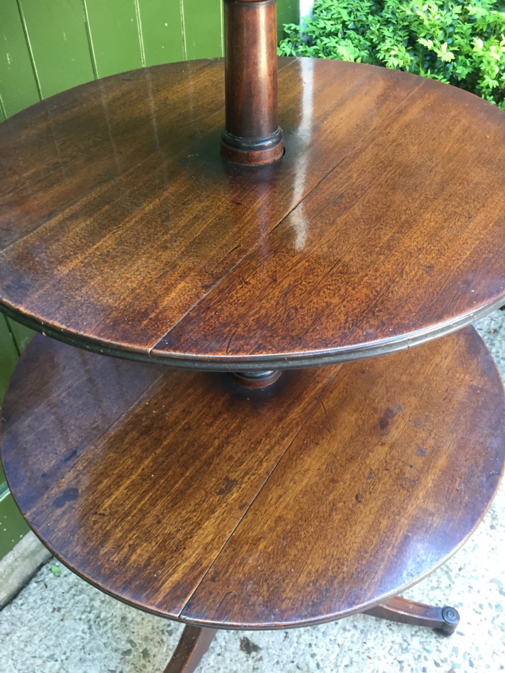 A late 18th-century George III mahogany three-tier circular dumb waiter featuring folding drop-leaf surfaces and a tripod base on castors. View XIV
