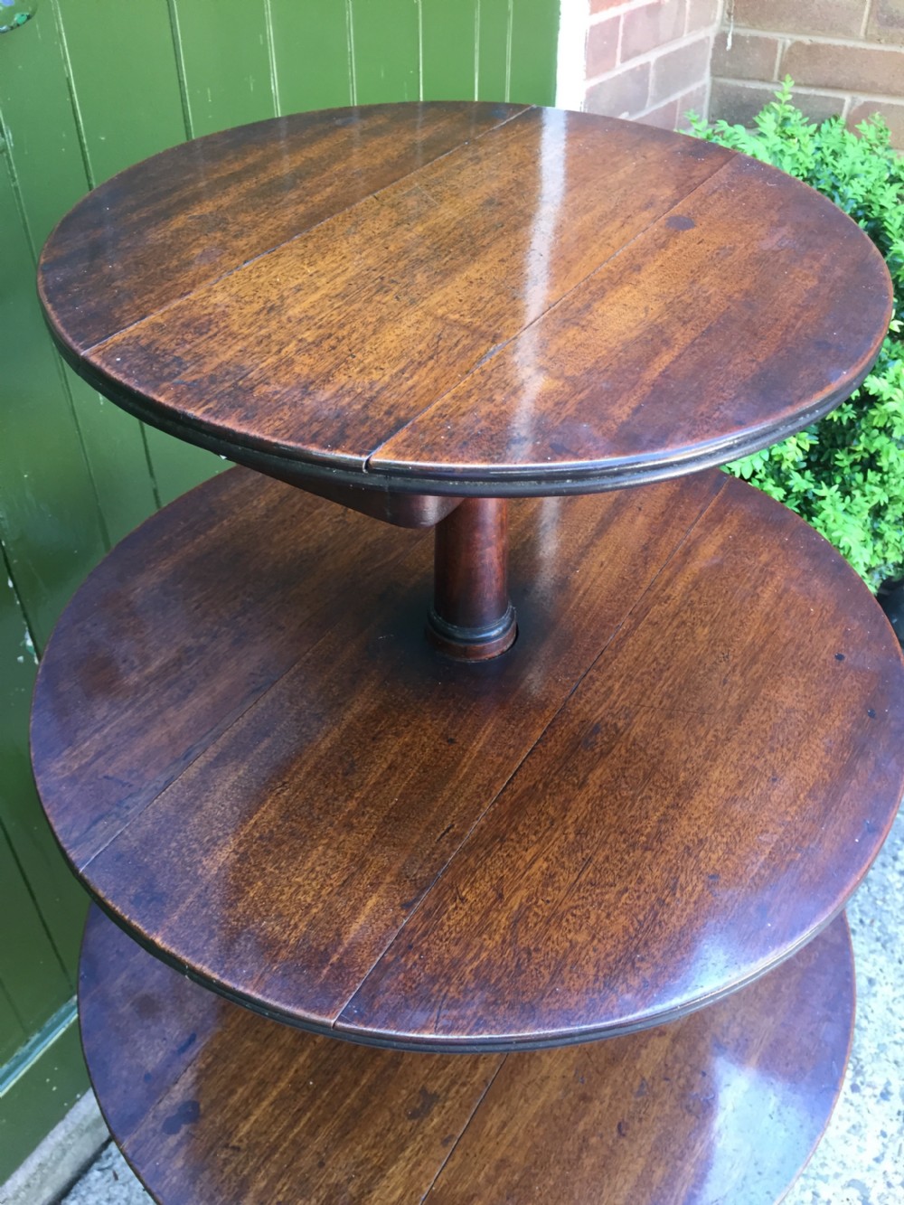 A late 18th-century George III mahogany three-tier circular dumb waiter featuring folding drop-leaf surfaces and a tripod base on castors. View XV