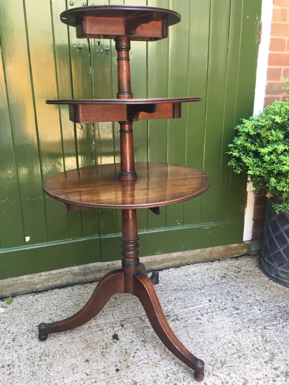 A late 18th-century George III mahogany three-tier circular dumb waiter featuring folding drop-leaf surfaces and a tripod base on castors. View XIX