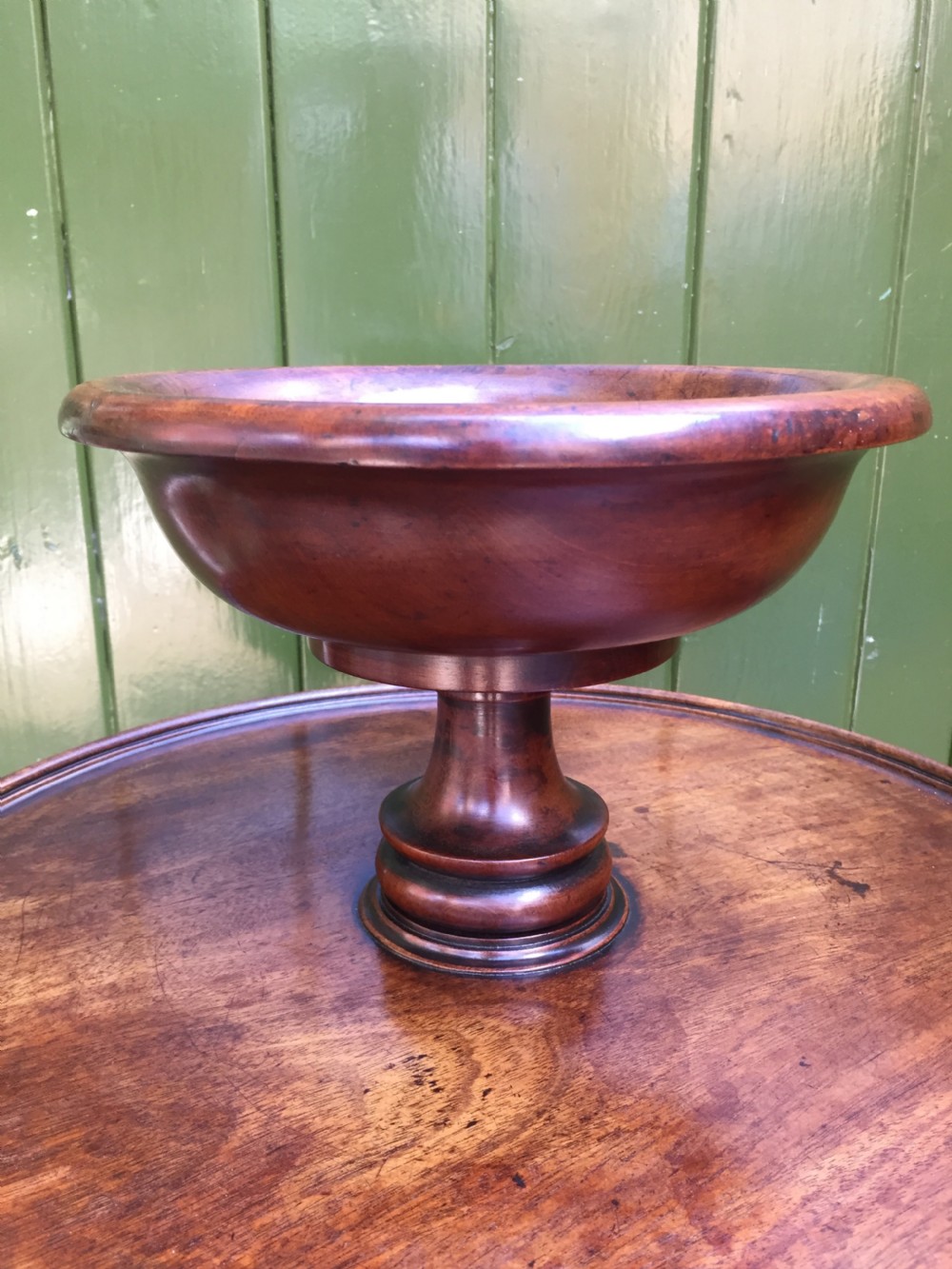 An early 19th-century French circular mahogany vide-poche table featuring a raised turned bowl, three column supports, and a triform base. View V