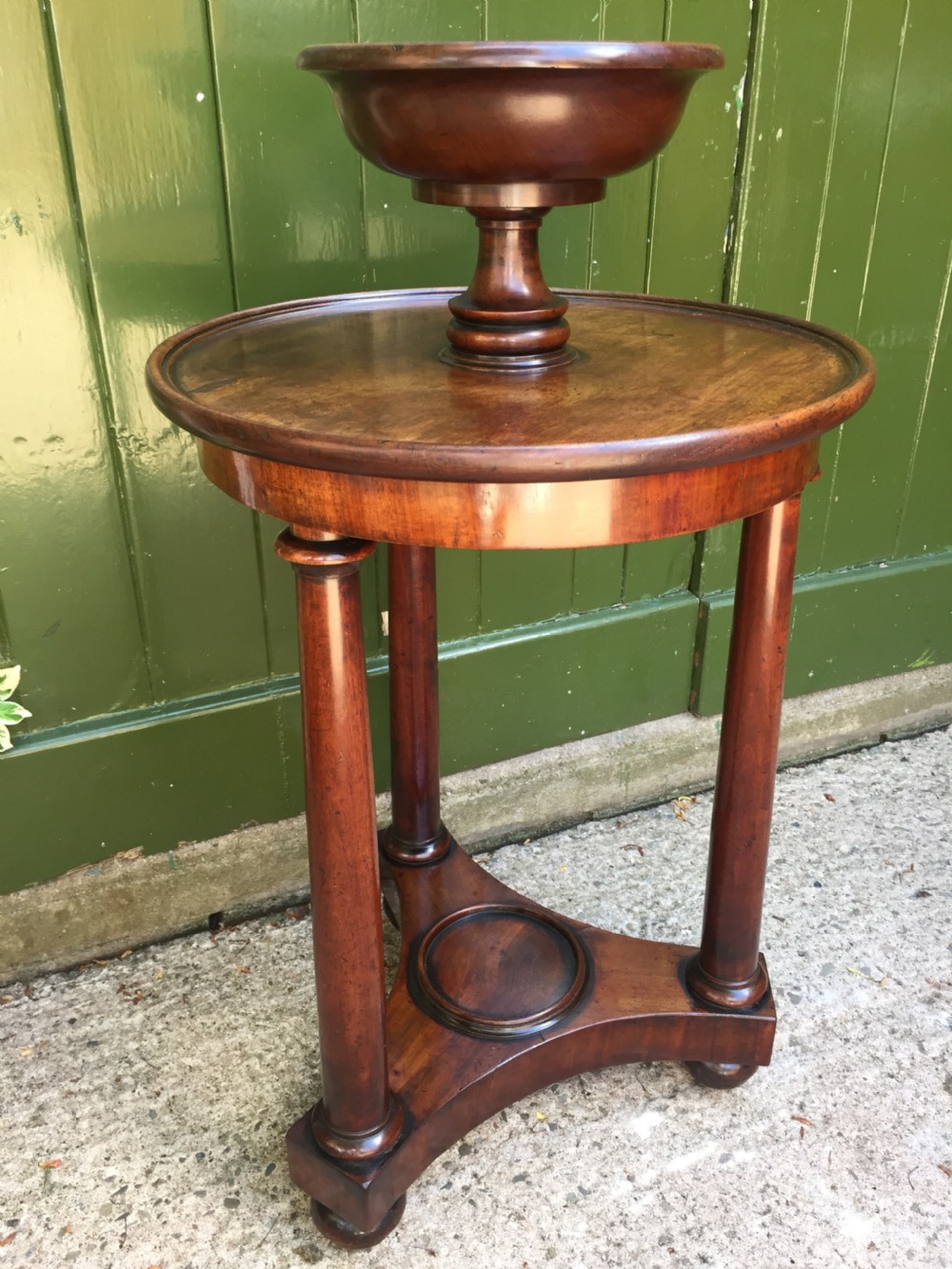 An early 19th-century French circular mahogany vide-poche table featuring a raised turned bowl, three column supports, and a triform base. View VII
