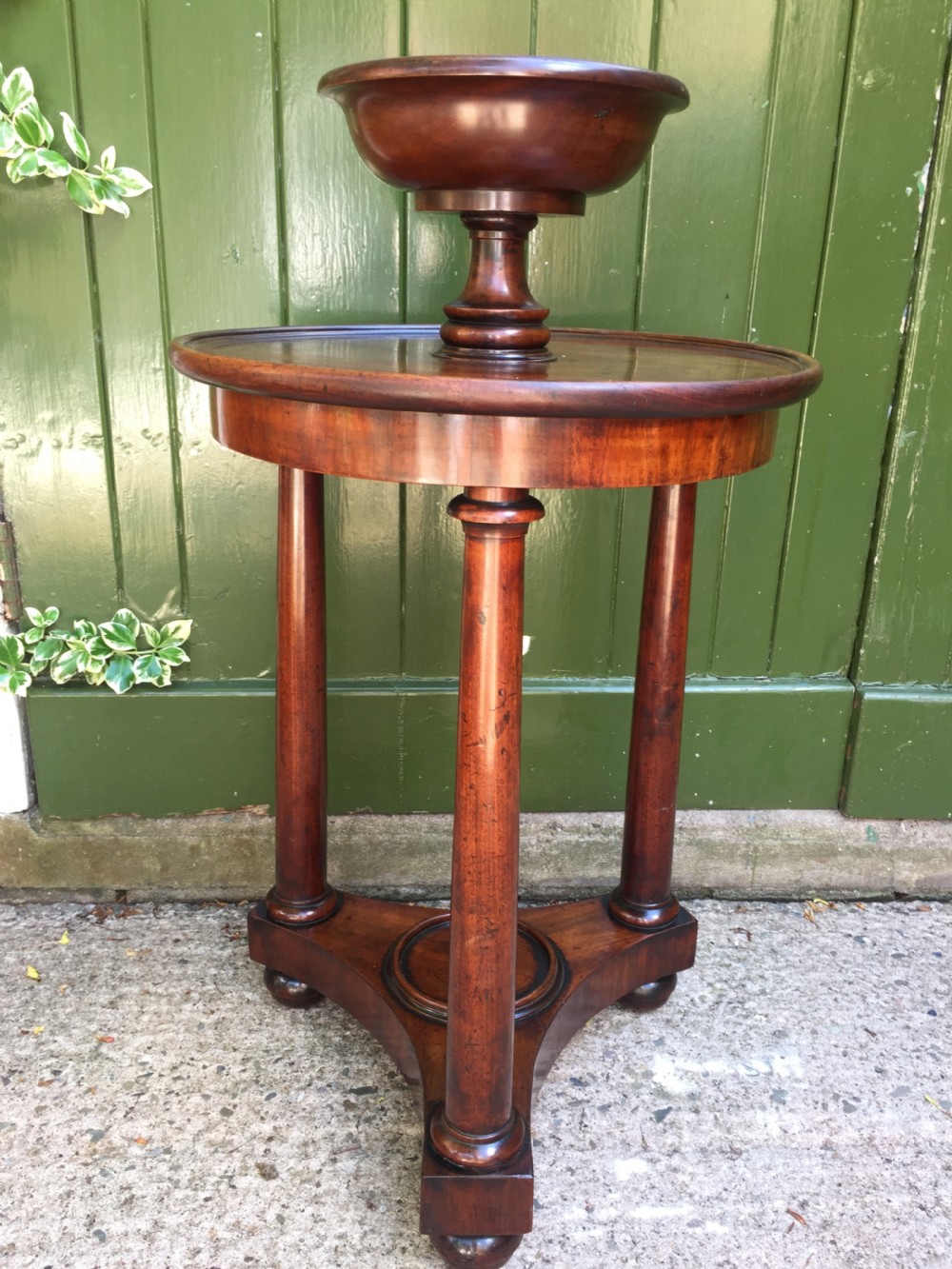 An early 19th-century French circular mahogany vide-poche table featuring a raised turned bowl, three column supports, and a triform base. View VIII