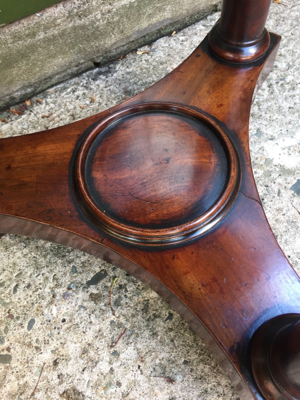 An early 19th-century French circular mahogany vide-poche table featuring a raised turned bowl, three column supports, and a triform base. View X