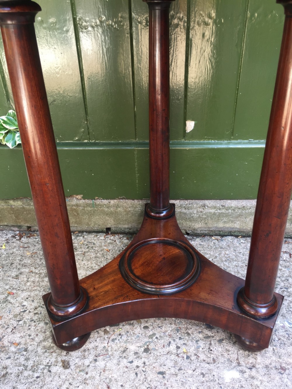 An early 19th-century French circular mahogany vide-poche table featuring a raised turned bowl, three column supports, and a triform base. View XII