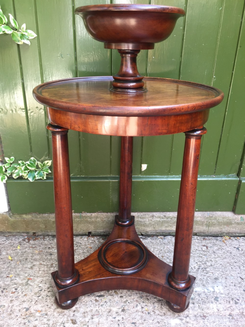 An early 19th-century French circular mahogany vide-poche table featuring a raised turned bowl, three column supports, and a triform base. View XIII