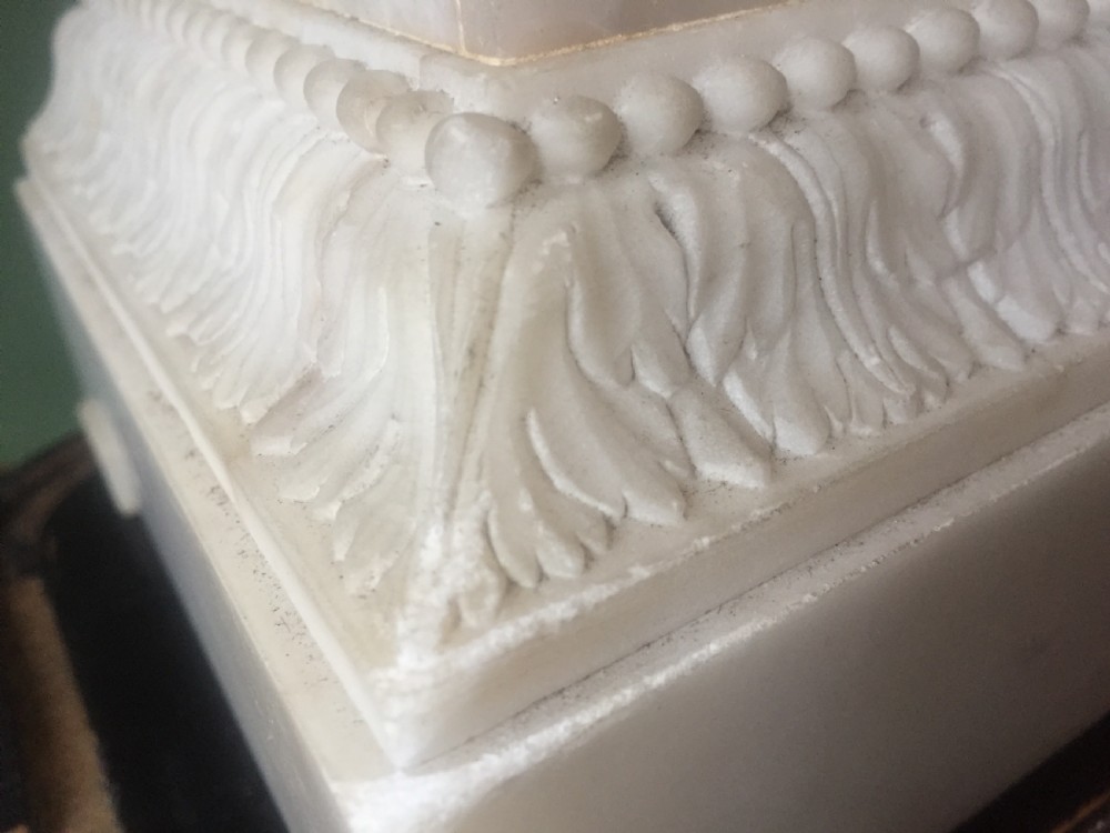 A nineteenth-century carved white alabaster mantel clock featuring a seated classical figure on a pedestal base enclosed under a tall glass dome. View IX