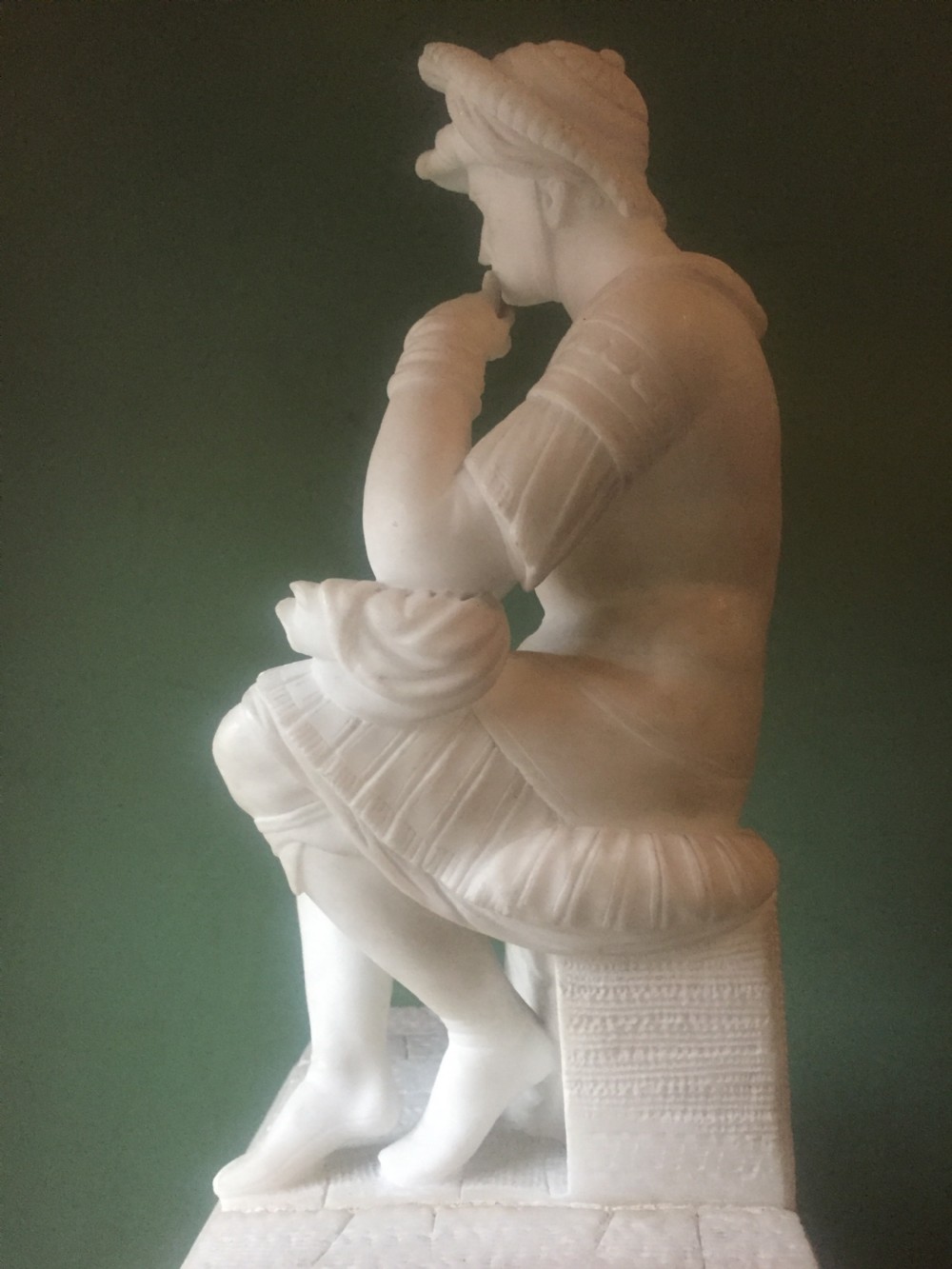 A nineteenth-century carved white alabaster mantel clock featuring a seated classical figure on a pedestal base enclosed under a tall glass dome. View XII
