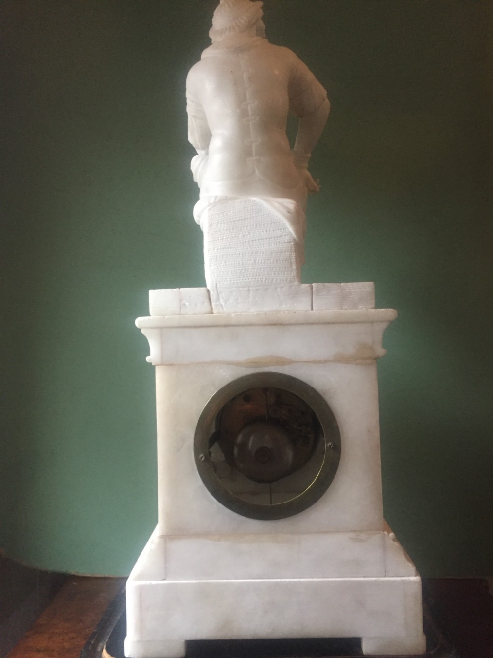A nineteenth-century carved white alabaster mantel clock featuring a seated classical figure on a pedestal base enclosed under a tall glass dome. View XVII