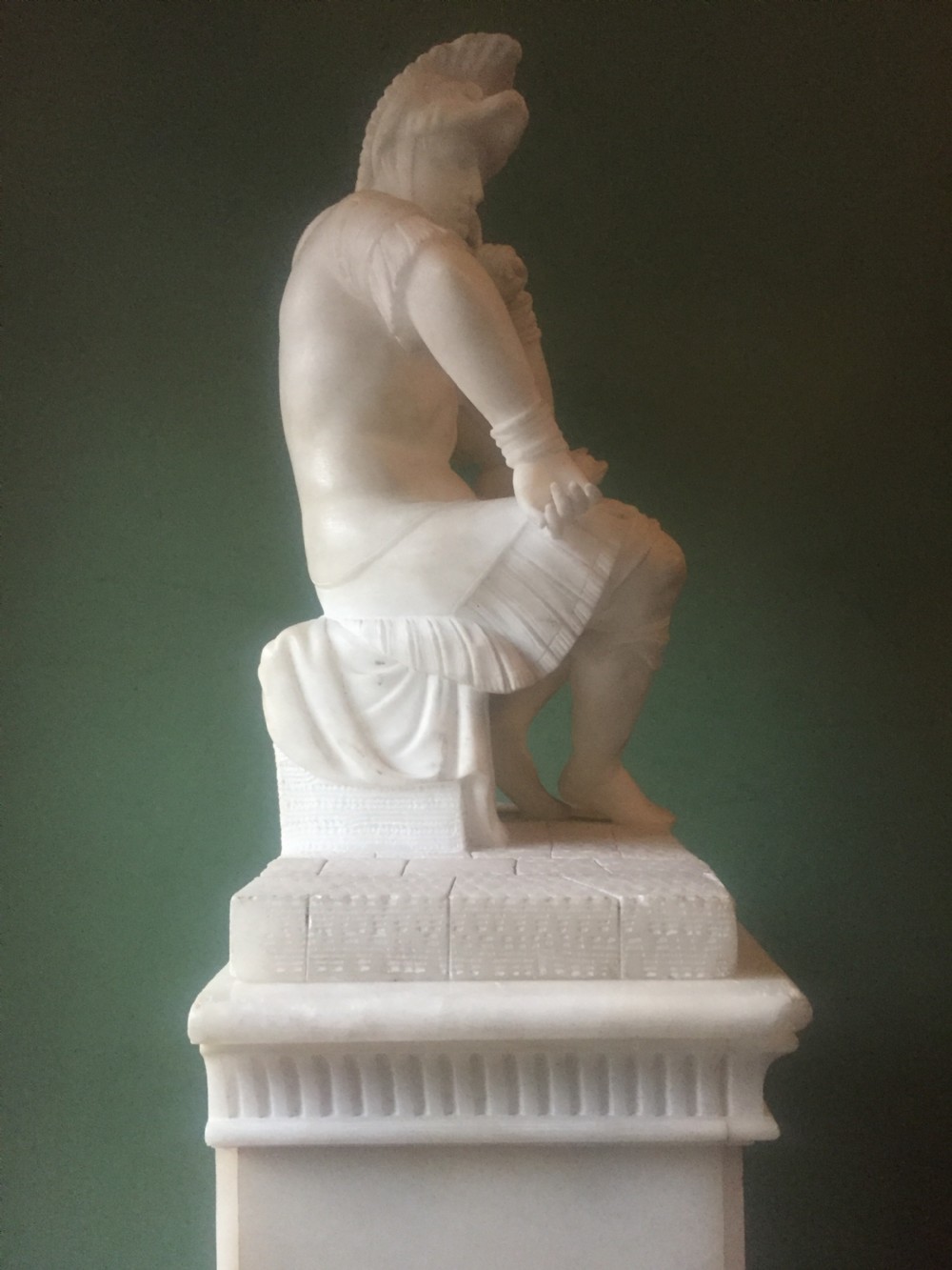A nineteenth-century carved white alabaster mantel clock featuring a seated classical figure on a pedestal base enclosed under a tall glass dome. View XIX