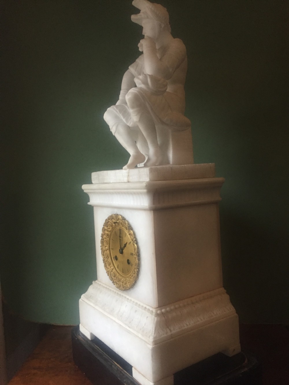 A nineteenth-century carved white alabaster mantel clock featuring a seated classical figure on a pedestal base enclosed under a tall glass dome. View XXVII