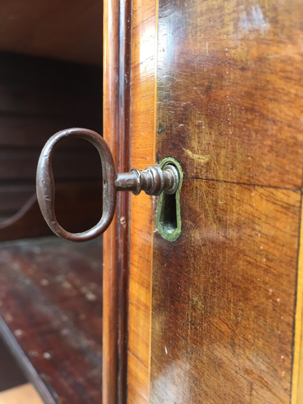 A late 18th-century George III mahogany and satinwood linen press with a swan-neck pediment, oval inlaid cupboard doors, and four lower drawers. View XVIII