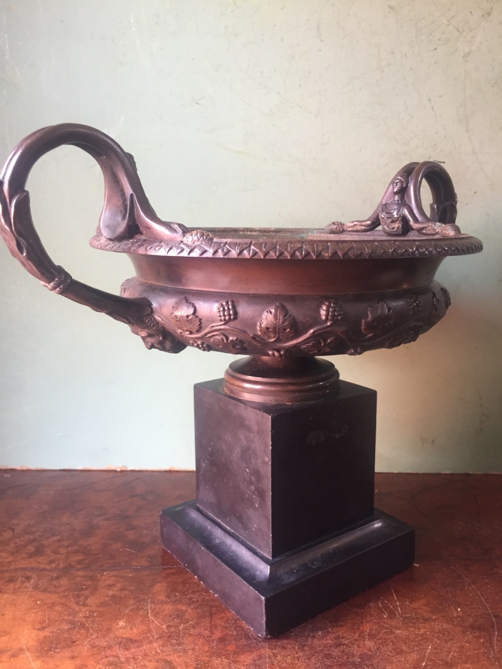 An early nineteenth-century Italian bronze twin-handled tazza featuring relief-carved vine leaves and grapes mounted on a square black base. View VII