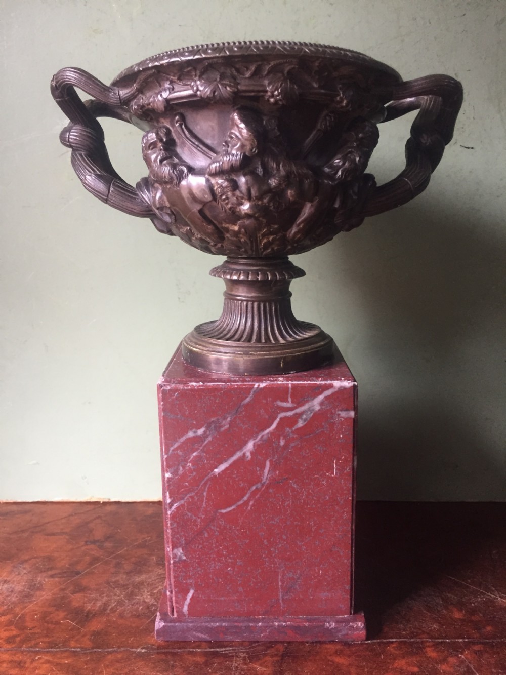 A nineteenth-century dark bronze reduction of the Warwick Vase with Bacchanalian masks and vine handles, mounted on a red marble square base.