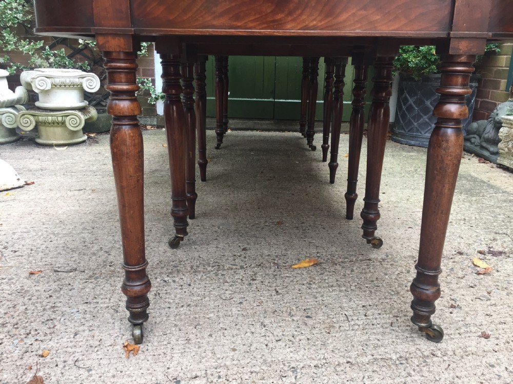 A Regency mahogany extending dining table with turned legs and brass castors. View VI