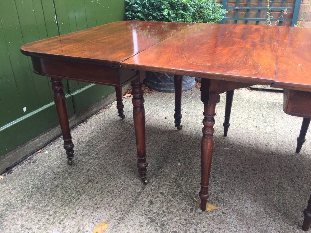 A Regency mahogany extending dining table with turned legs and brass castors. View VIII