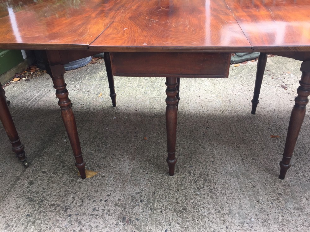 A Regency mahogany extending dining table with turned legs and brass castors. View IX