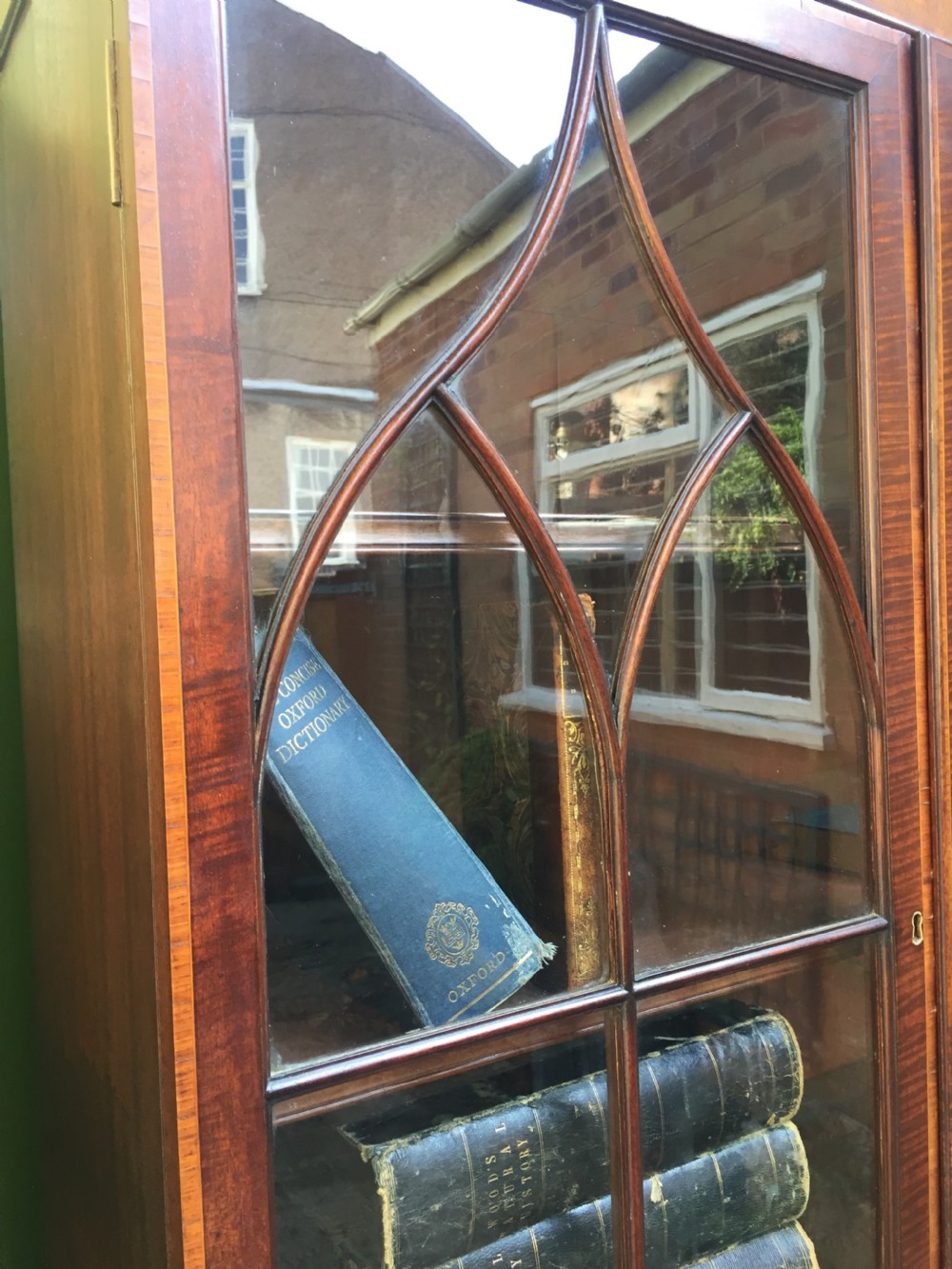 A late Victorian mahogany glazed cabinet featuring upper astragal doors with gothic tracery above two drawers and oval inlaid cupboard doors. View VI