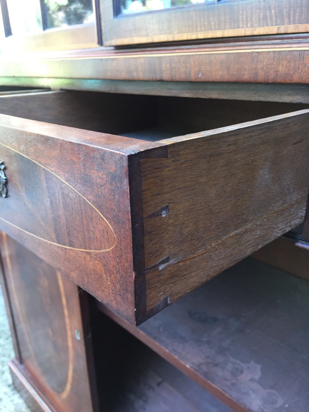 A late Victorian mahogany glazed cabinet featuring upper astragal doors with gothic tracery above two drawers and oval inlaid cupboard doors. View XIV