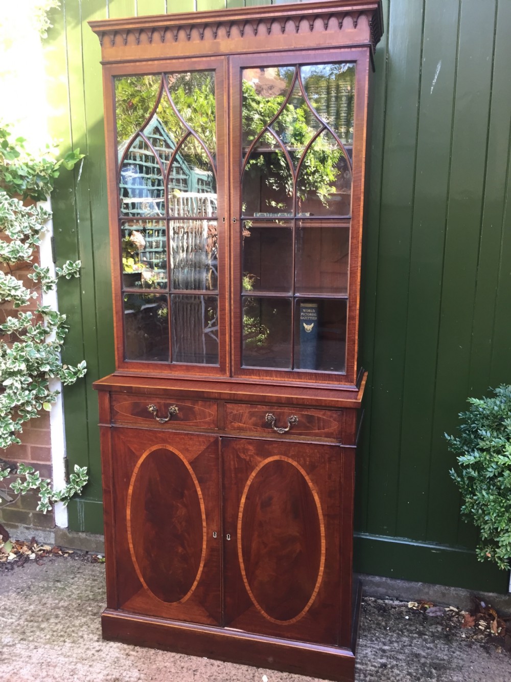 A late Victorian mahogany glazed cabinet featuring upper astragal doors with gothic tracery above two drawers and oval inlaid cupboard doors. View XV