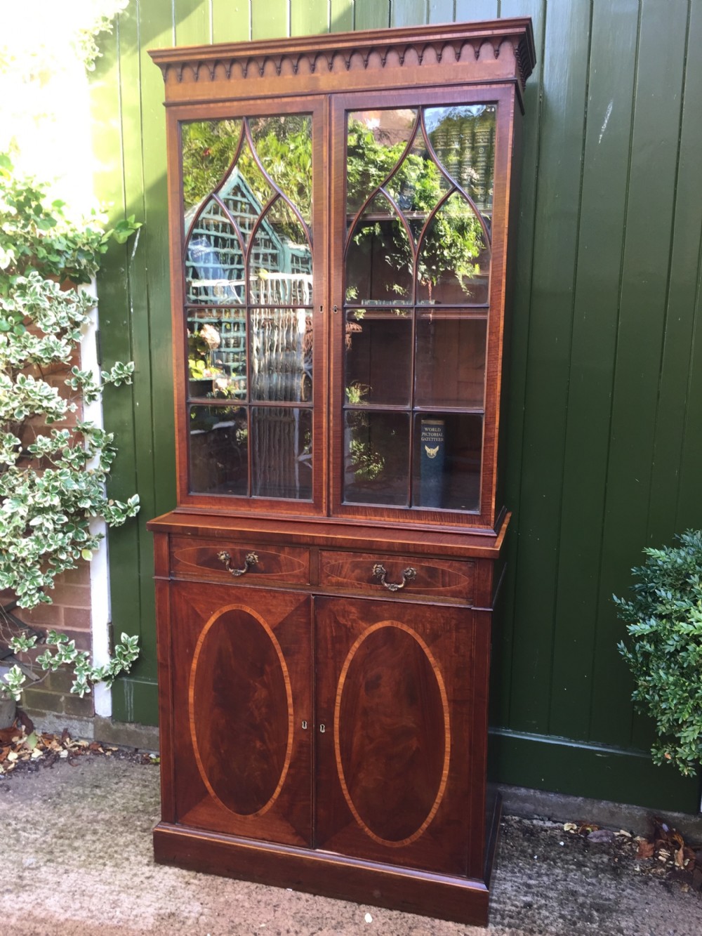 A late Victorian mahogany glazed cabinet featuring upper astragal doors with gothic tracery above two drawers and oval inlaid cupboard doors. View XVII