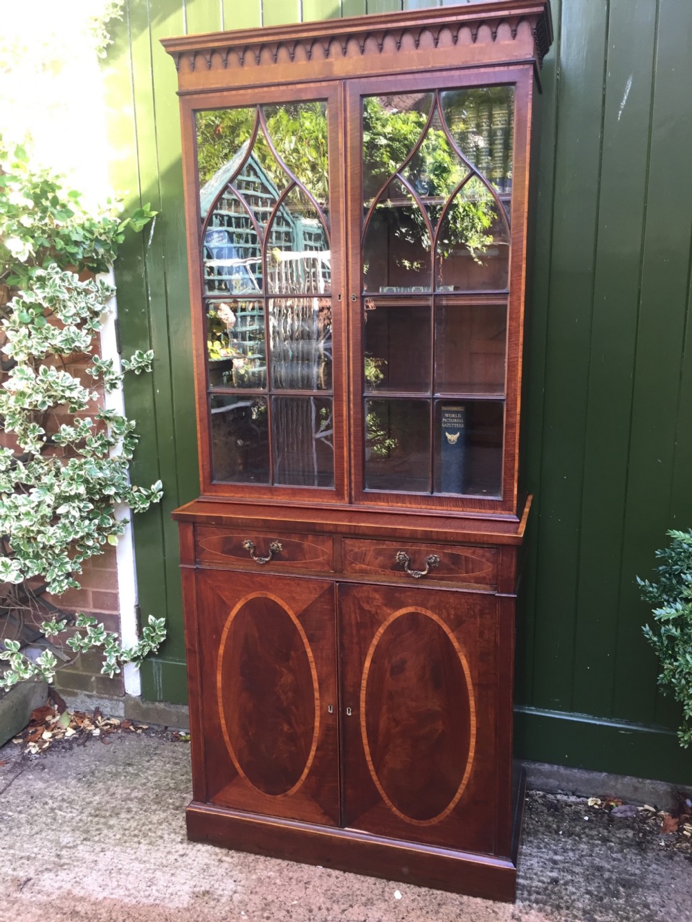 A late Victorian mahogany glazed cabinet featuring upper astragal doors with gothic tracery above two drawers and oval inlaid cupboard doors. View XVIII