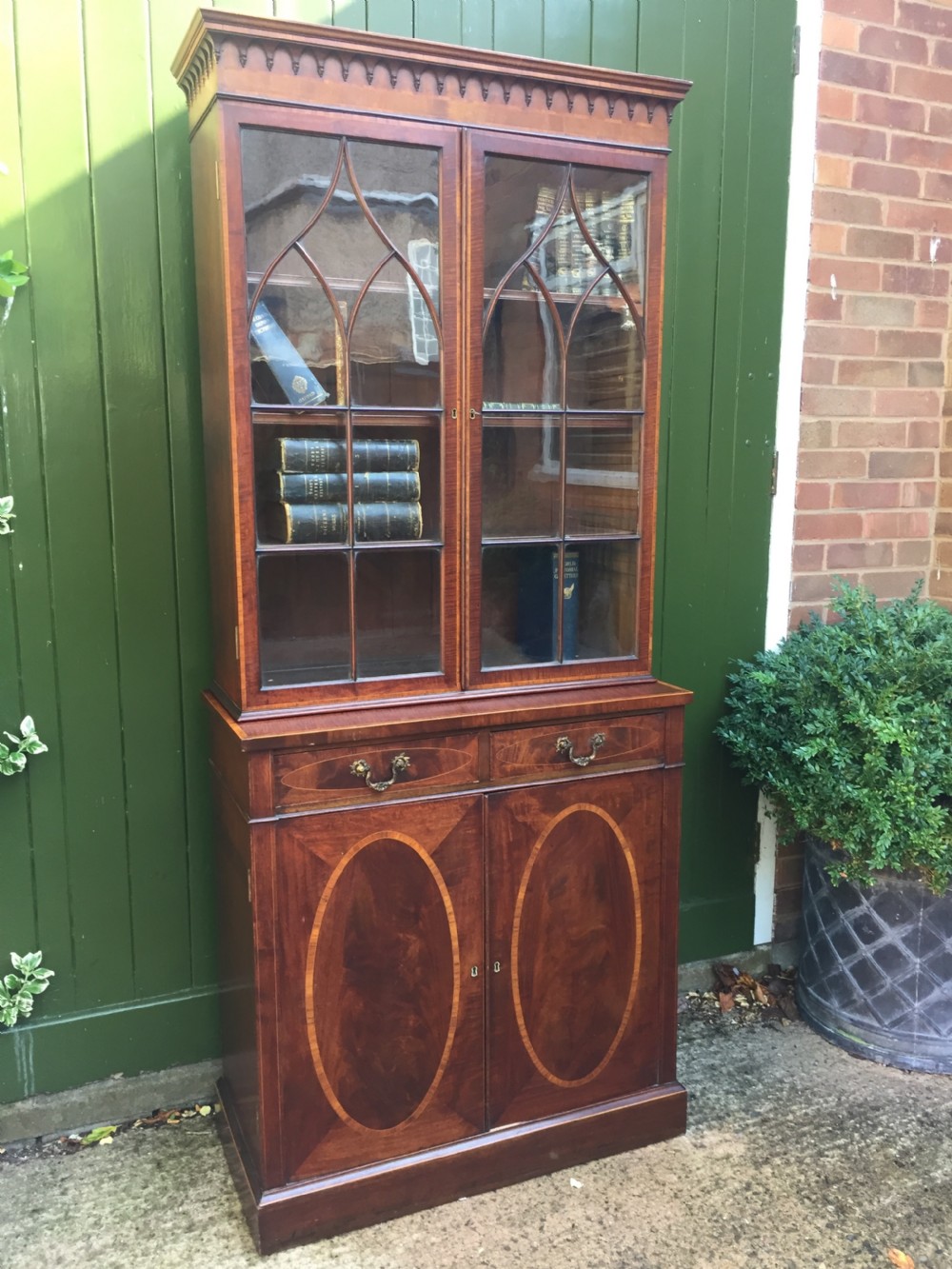 A late Victorian mahogany glazed cabinet featuring upper astragal doors with gothic tracery above two drawers and oval inlaid cupboard doors. View XX