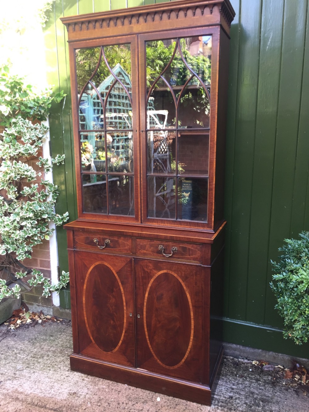 A late Victorian mahogany glazed cabinet featuring upper astragal doors with gothic tracery above two drawers and oval inlaid cupboard doors. View XXI