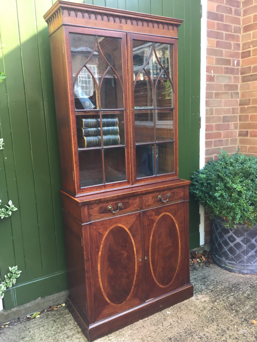 A late Victorian mahogany glazed cabinet featuring upper astragal doors with gothic tracery above two drawers and oval inlaid cupboard doors. View XXII
