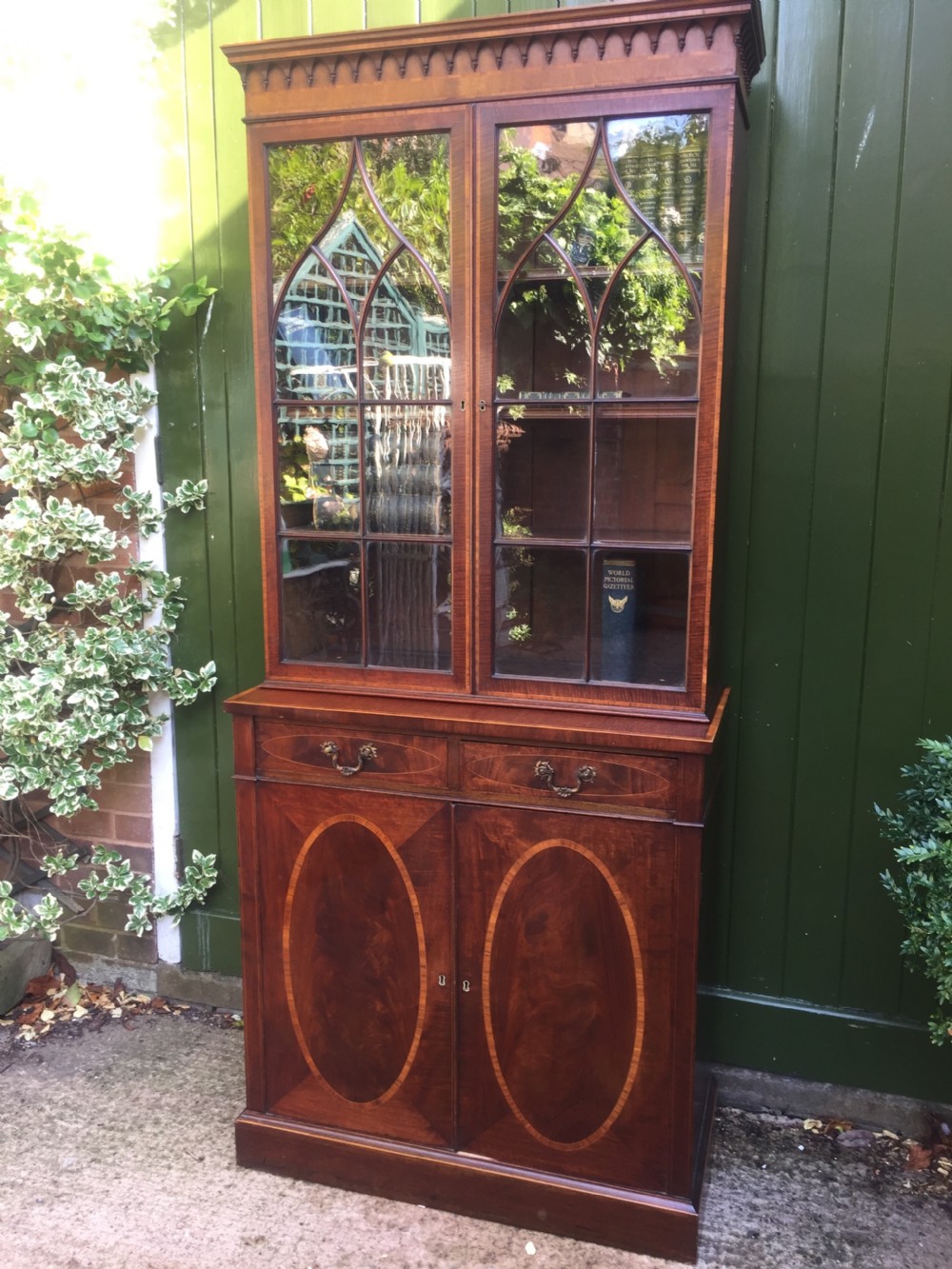 A late Victorian mahogany glazed cabinet featuring upper astragal doors with gothic tracery above two drawers and oval inlaid cupboard doors. View XXIV