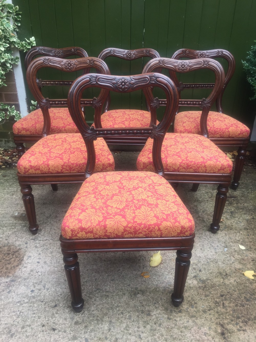 A set of six early nineteenth-century George IV mahogany dining chairs featuring carved balloon back frames, reeded legs, and red pattern upholstered seats. View II