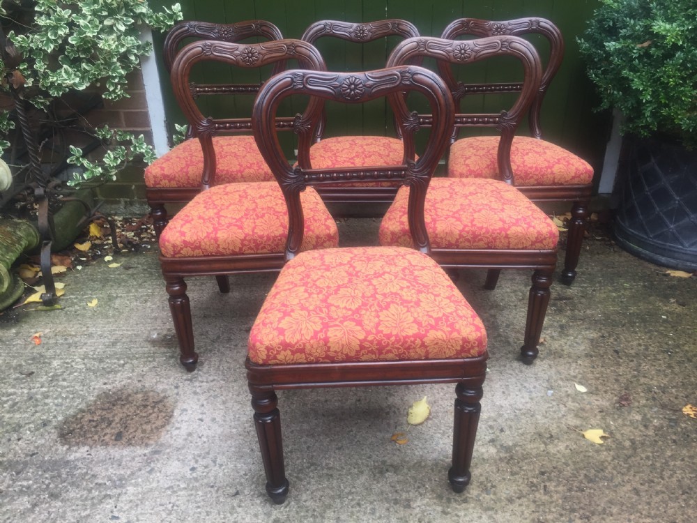 A set of six early nineteenth-century George IV mahogany dining chairs featuring carved balloon back frames, reeded legs, and red pattern upholstered seats. View III